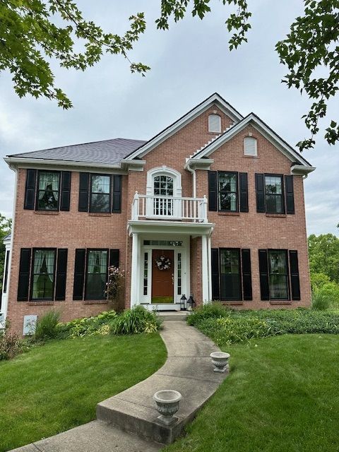 A large brick house with black shutters on the windows