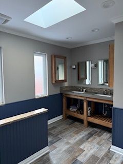 A bathroom with two sinks and a skylight.