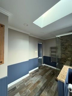 A bathroom with a skylight and a walk in shower.