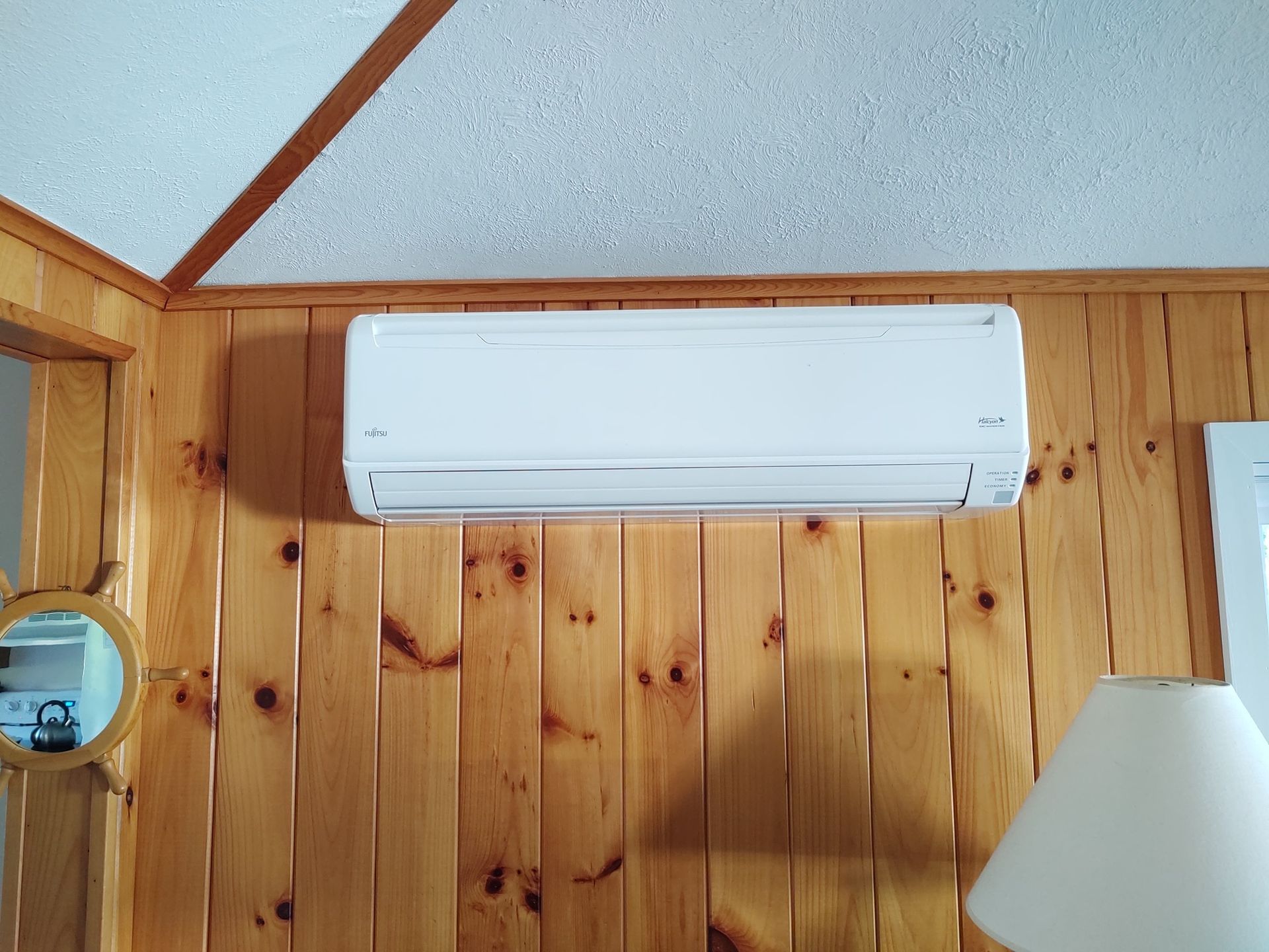A white air conditioner is hanging on a wooden wall in a room.