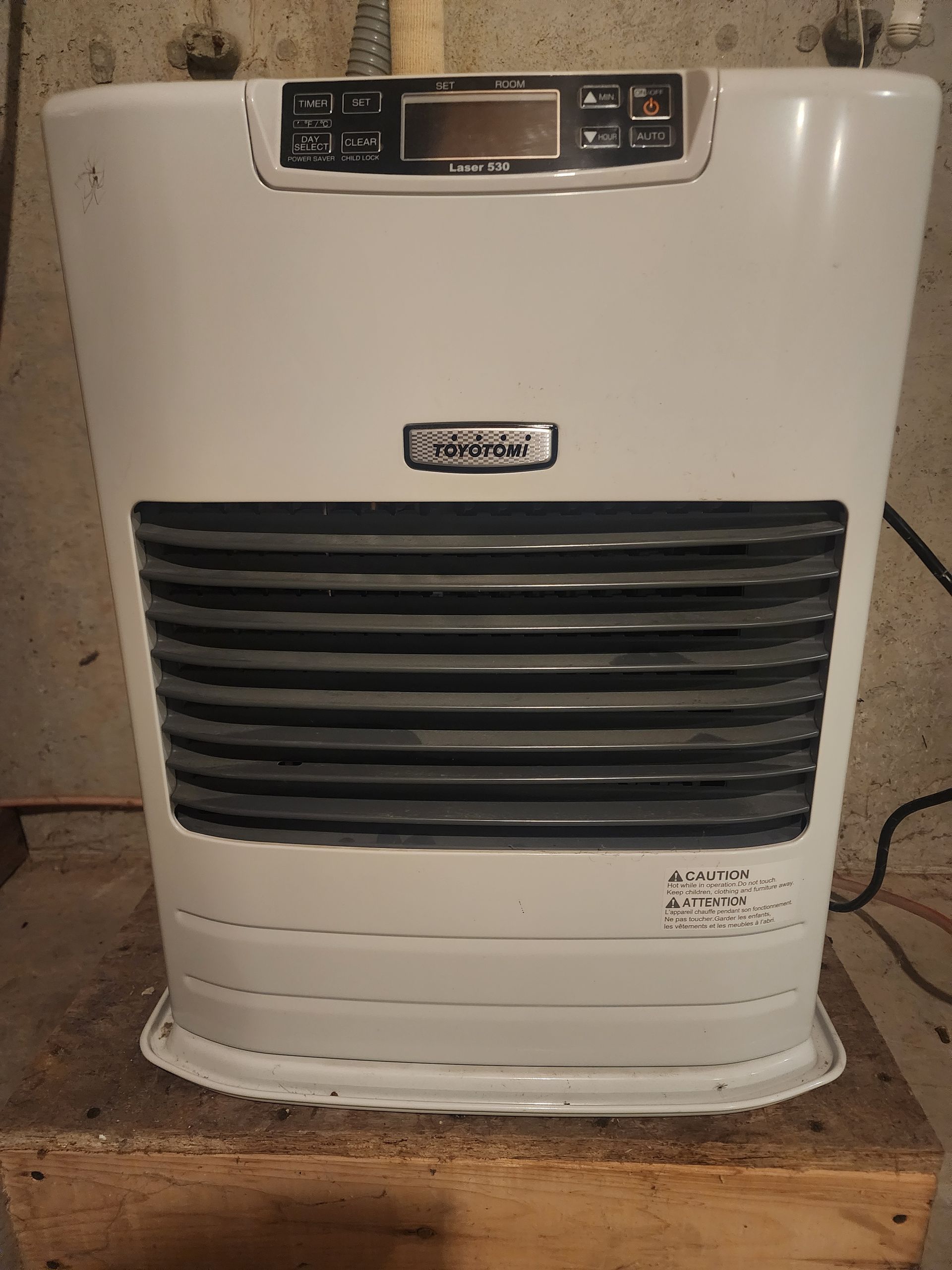 A person is pressing a button on a digital thermostat.