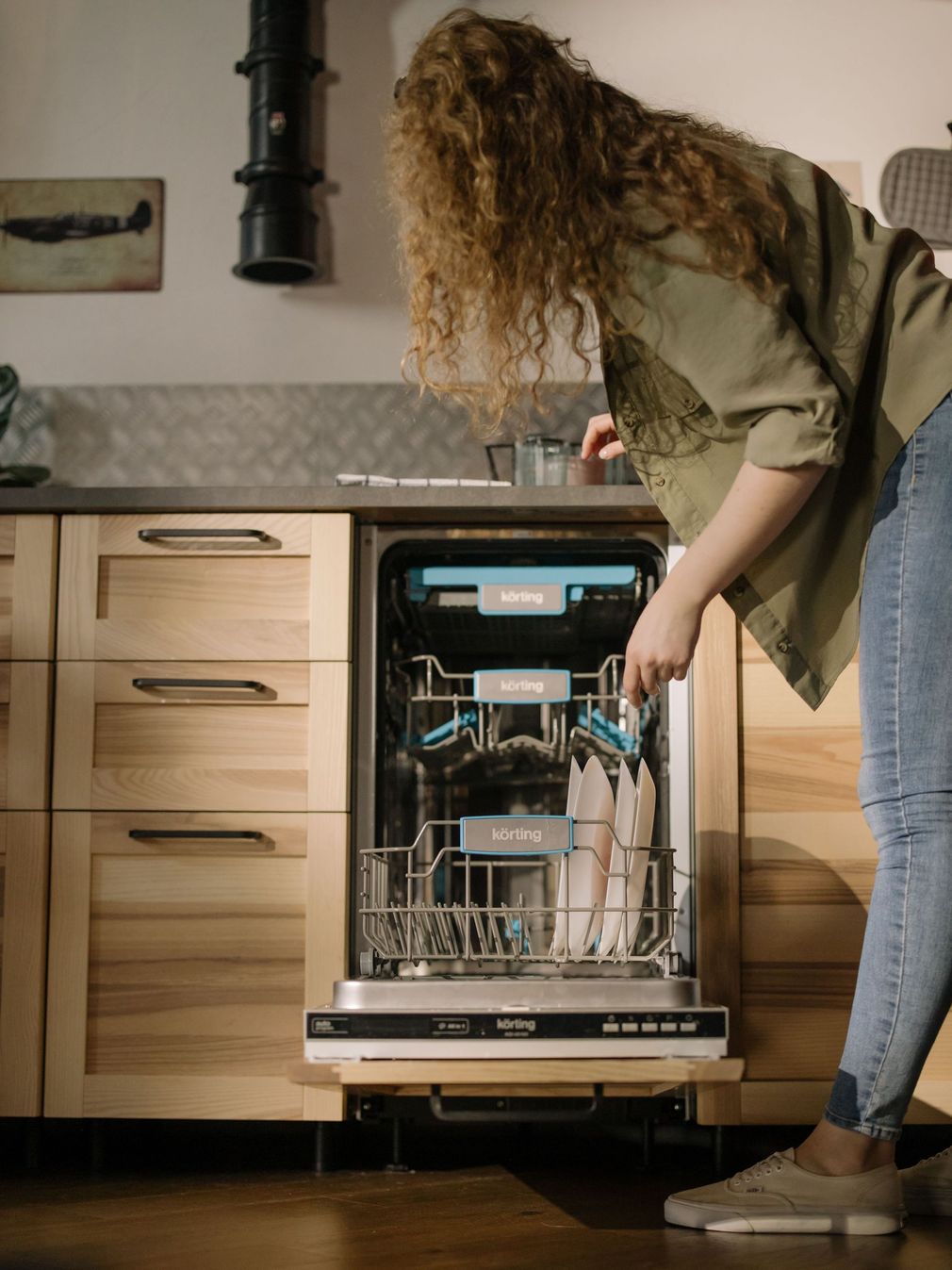 Person loading dishes into an open dishwasher in a modern kitchen