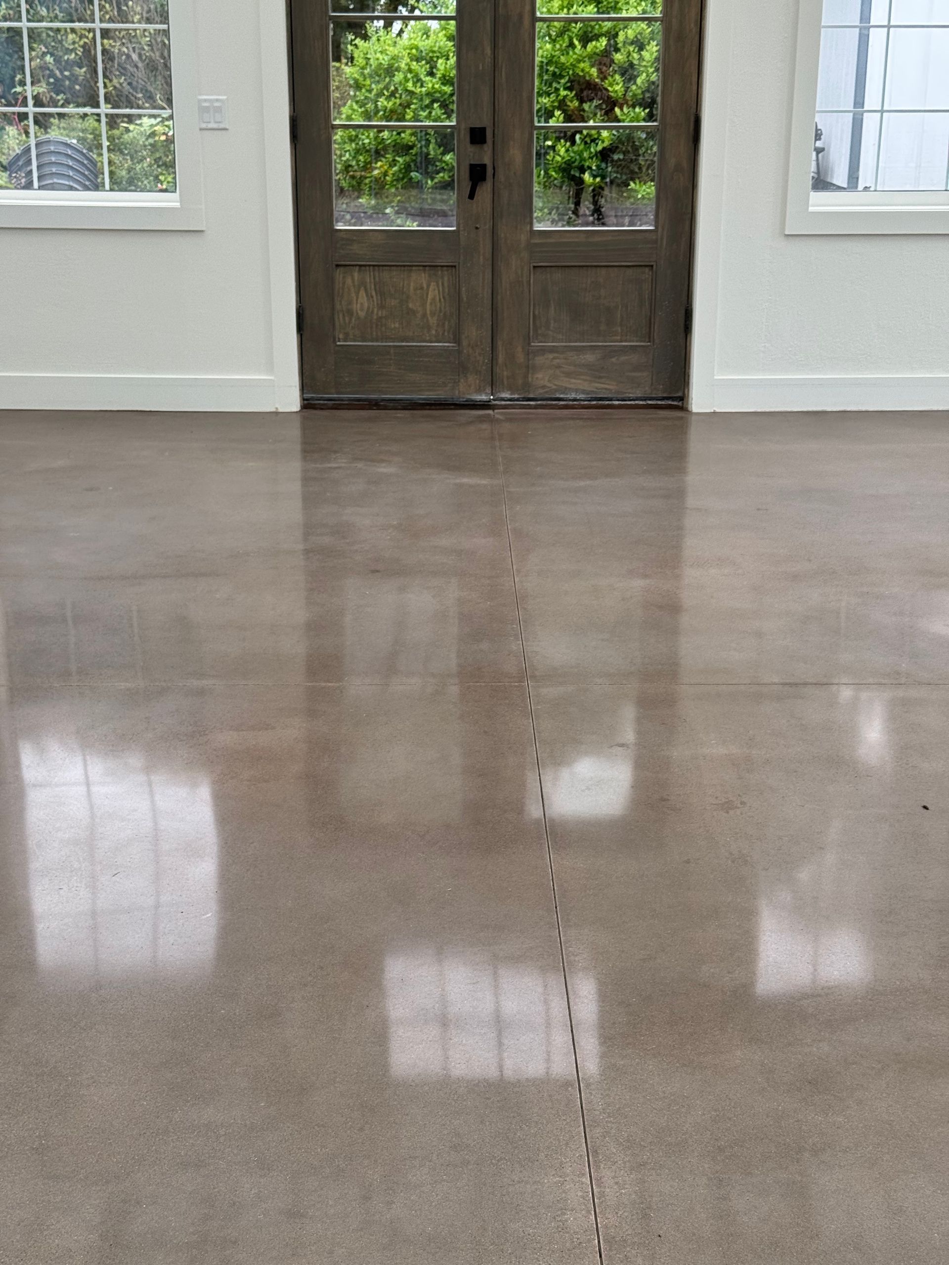 A polished concrete floor with a single visible crack running vertically through the center, in front of wooden doors.