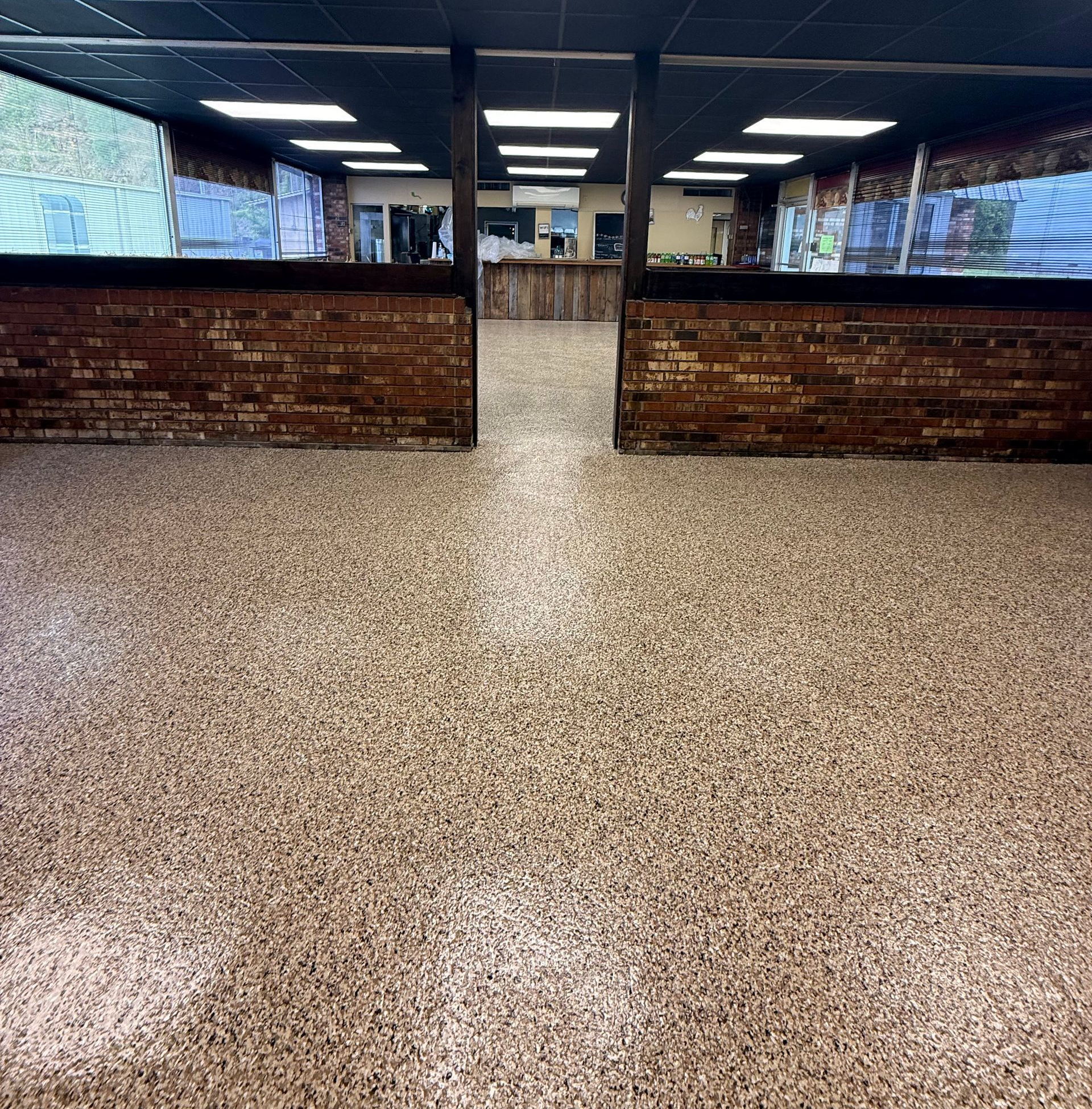 Empty indoor arcade or game room with brick counters, screens, and speckled flooring.