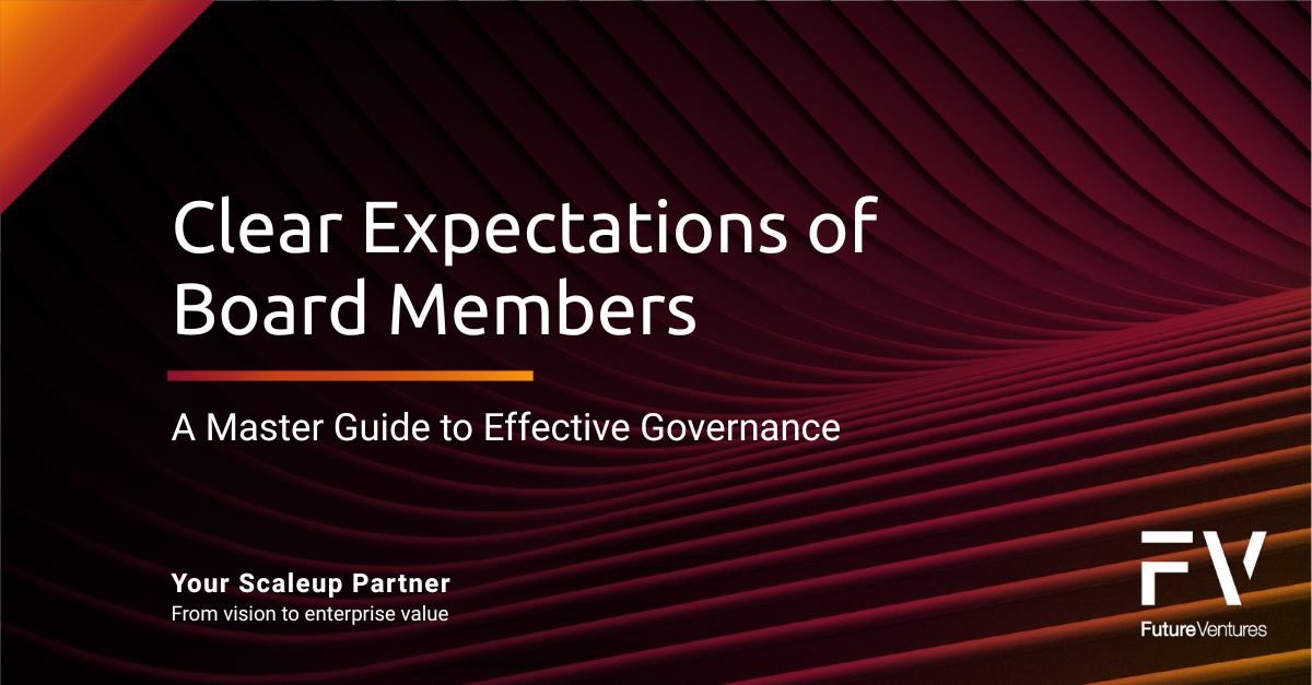 People gathered around a table with laptops, one woman in red points while others observe in a modern office.