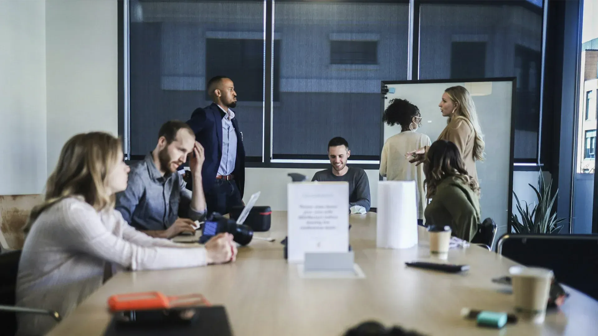 A group of people are sitting around a conference table in a conference room.