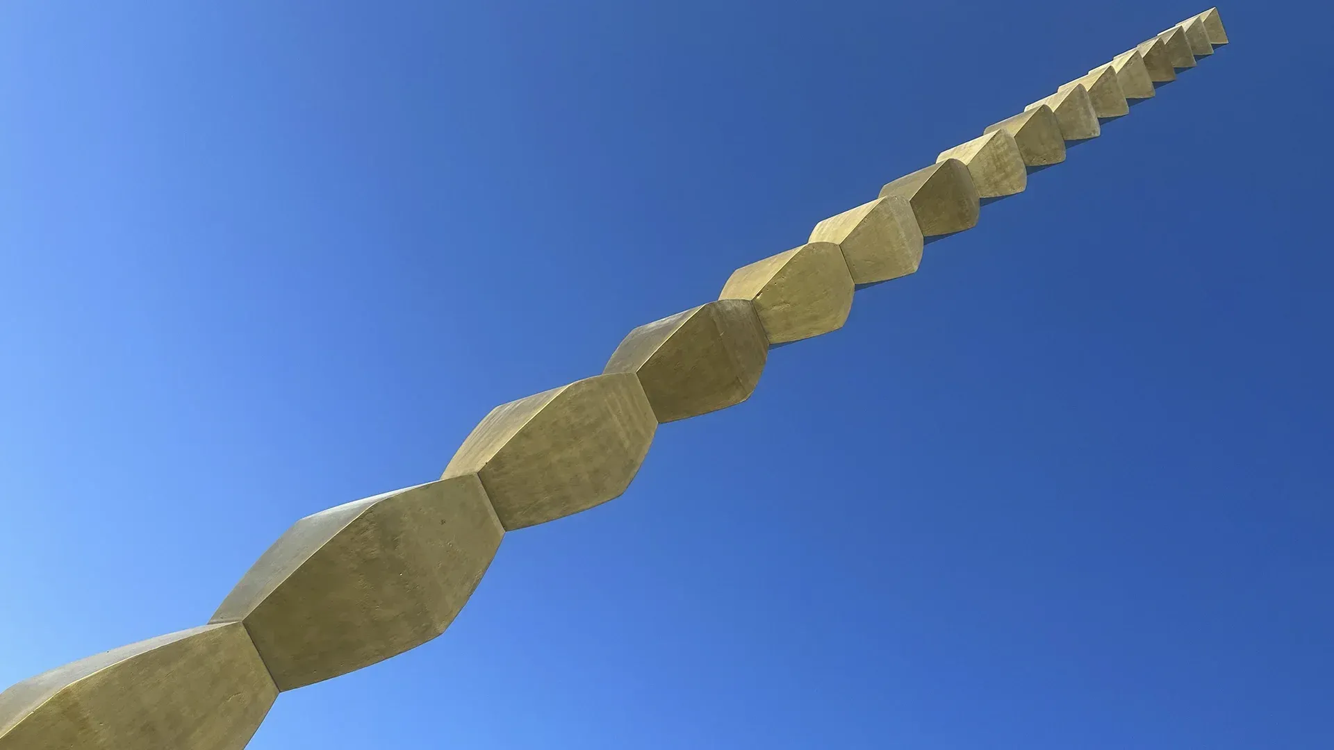 A very long sculpture against a blue sky.