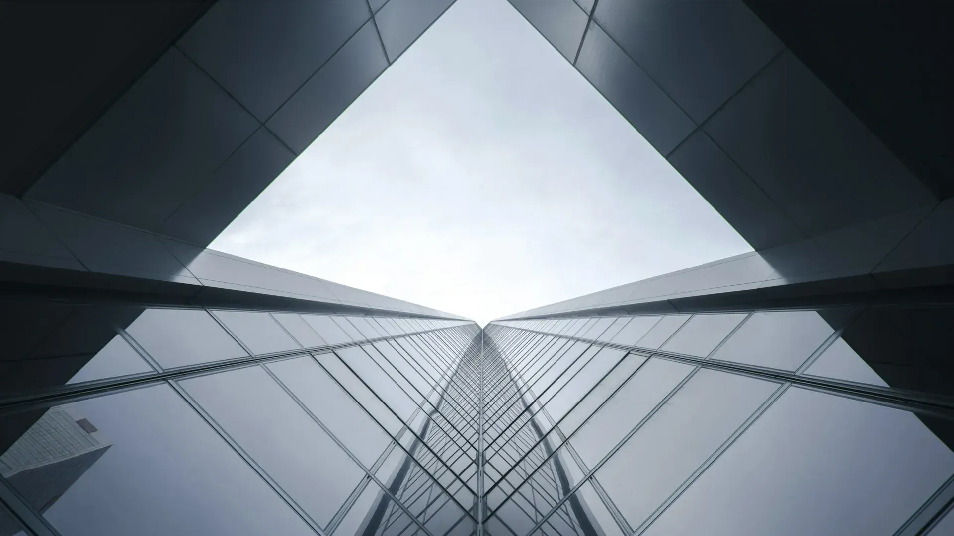 Low-angle view of modern skyscrapers with mirrored glass, converging towards the sky.
