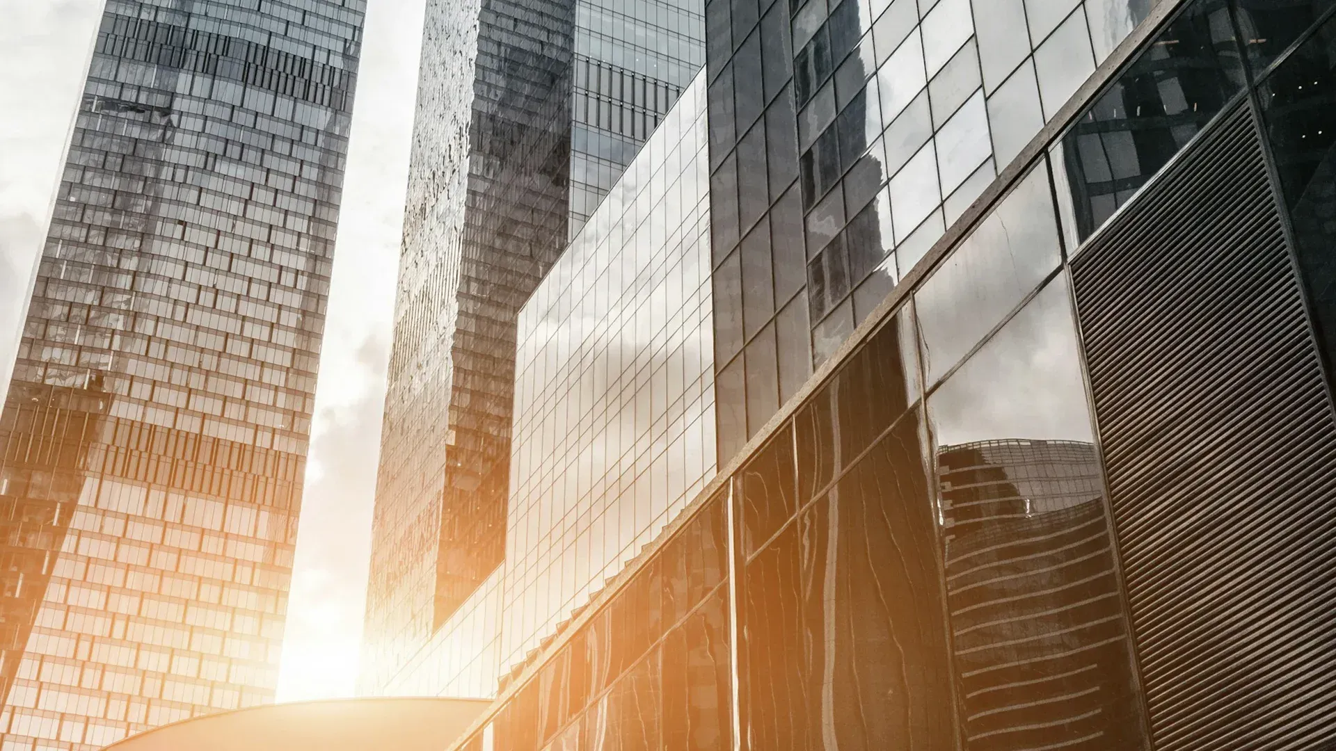Skyscrapers with glass facades reflecting sunlight, modern urban setting.