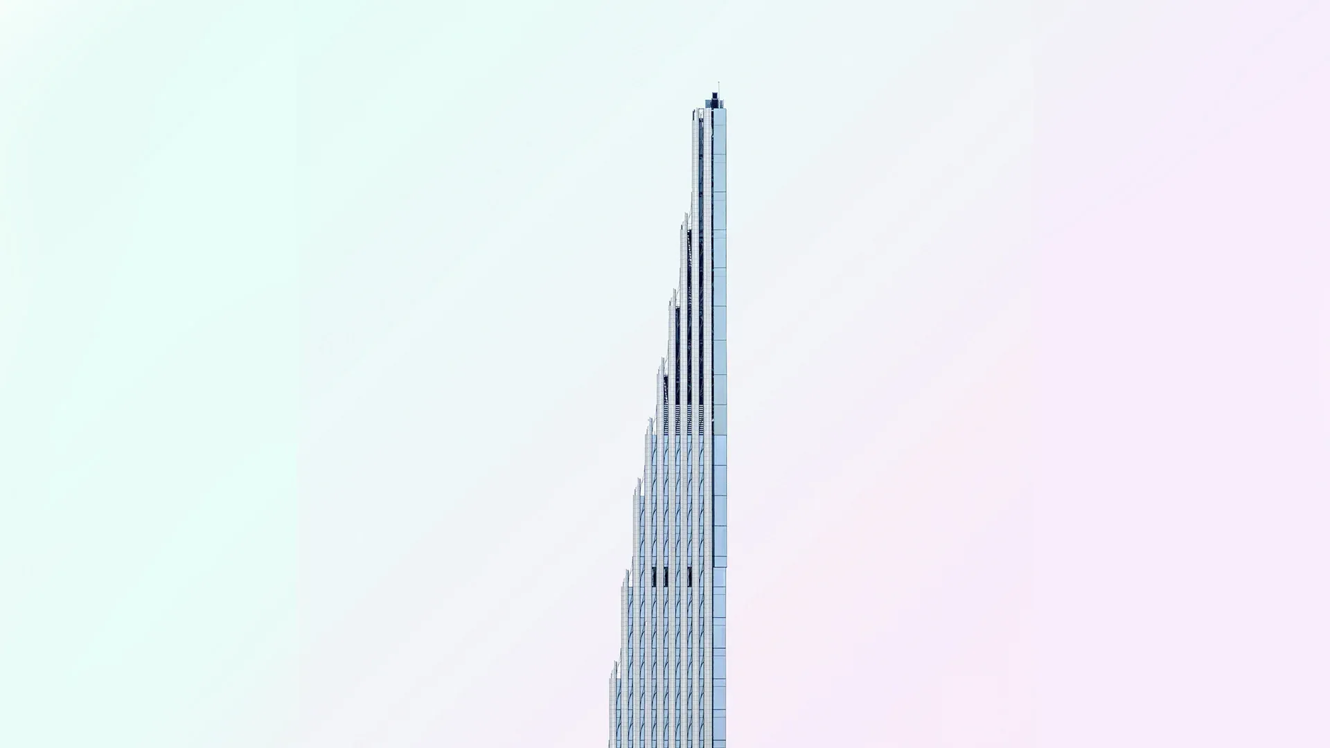 Tall, narrow skyscraper against a pale, gradient sky.