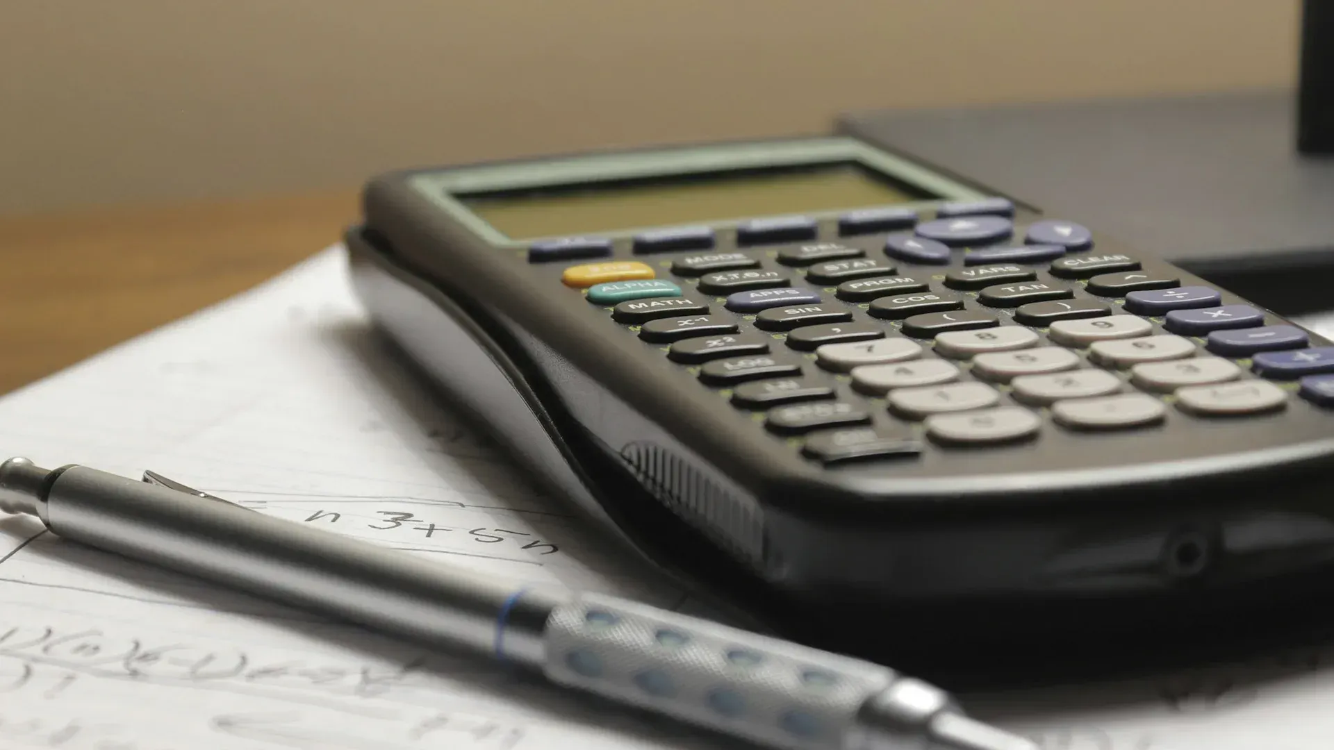 Calculator on paper with a pen, presumably used for calculations in a learning or work setting.