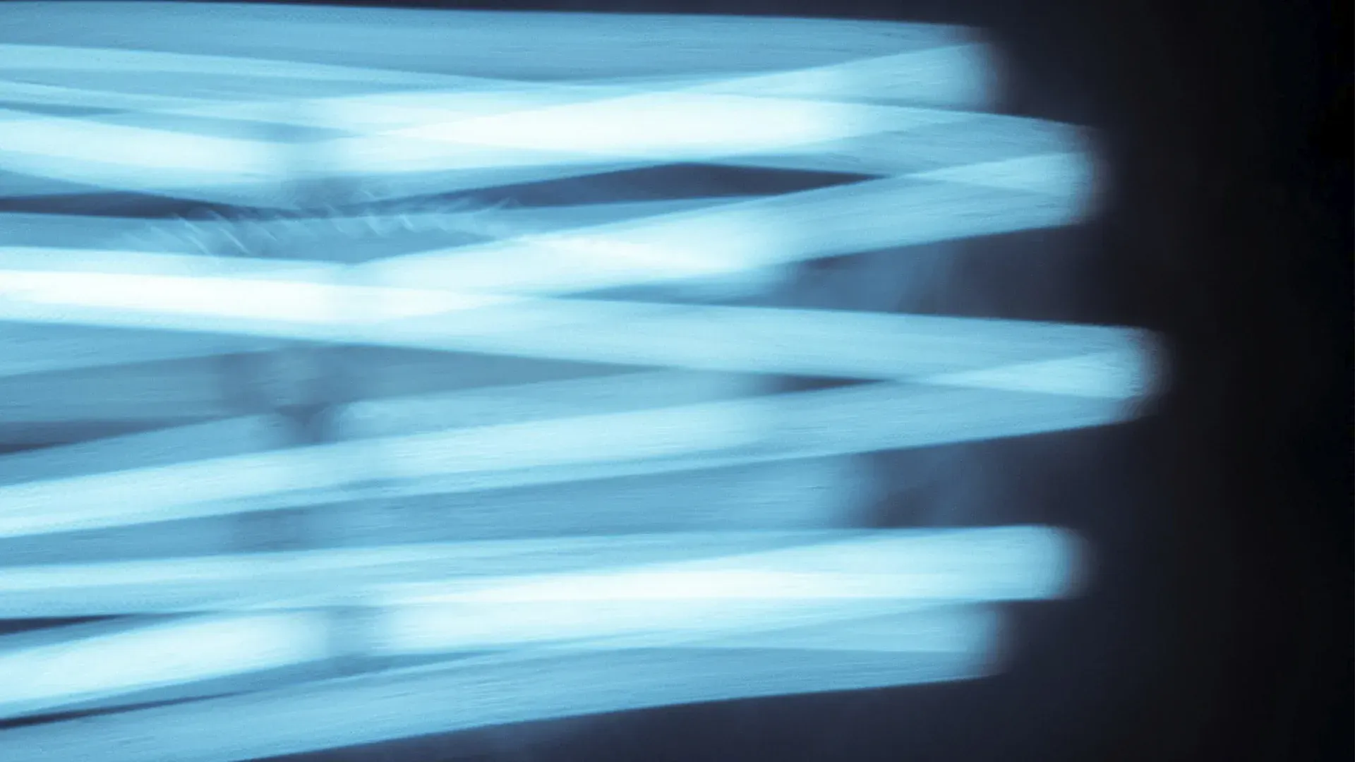 Blurred, glowing blue neon tubes against a dark background.