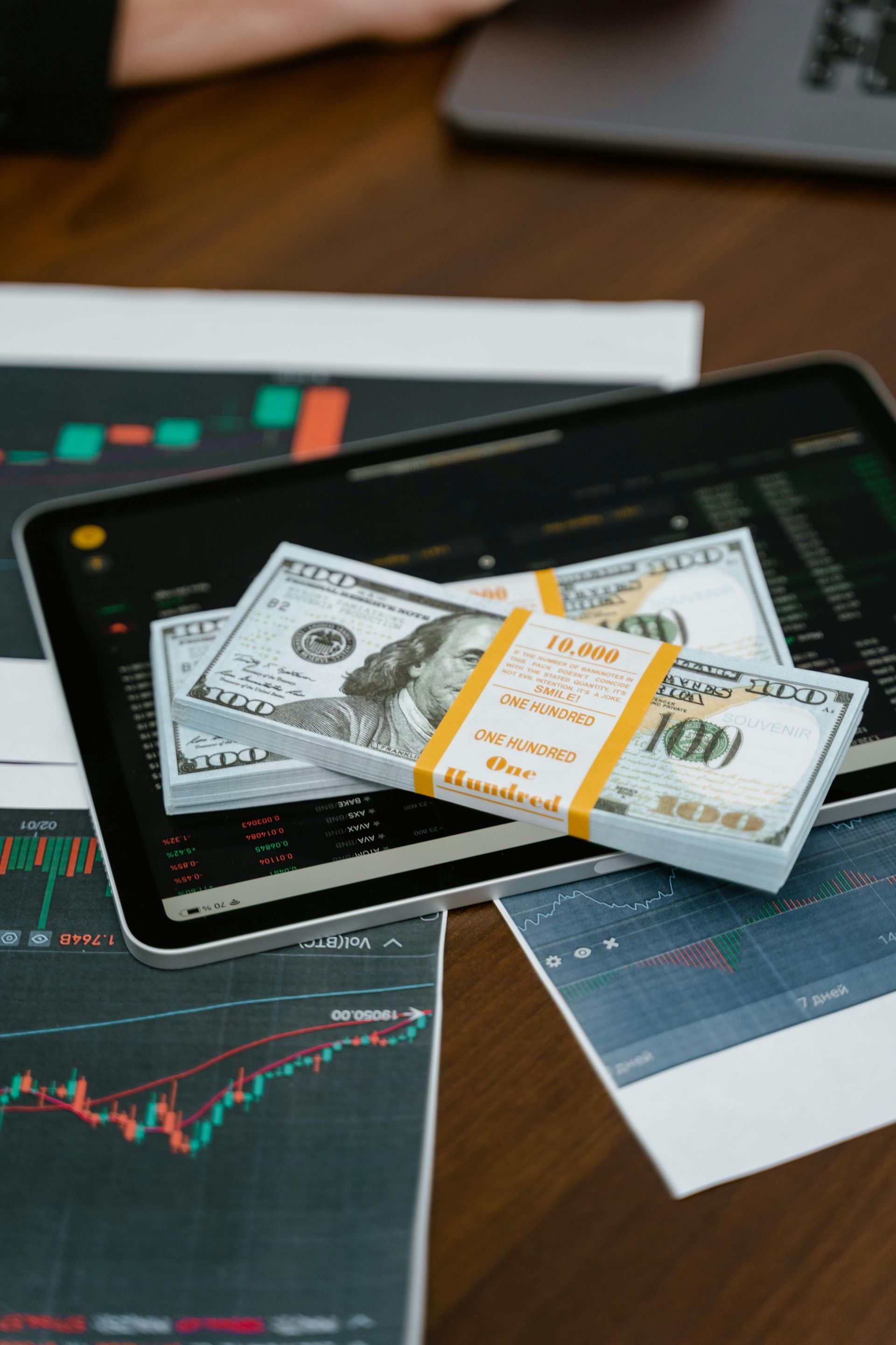 Image of money over a tablet and statistics charts.