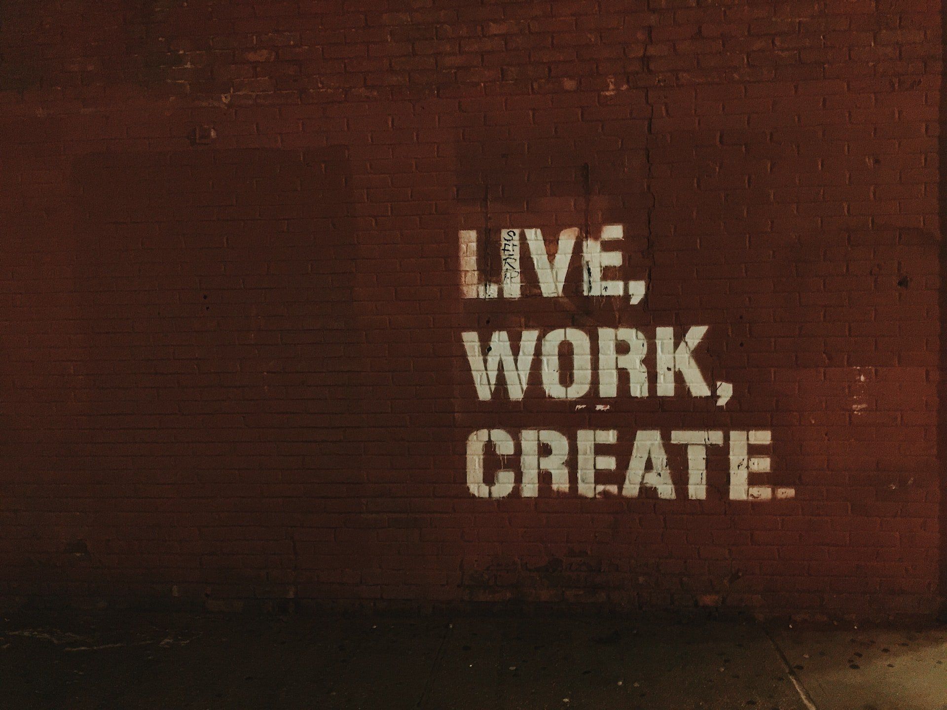 Stenciled Live Work Create sign on a brick wall