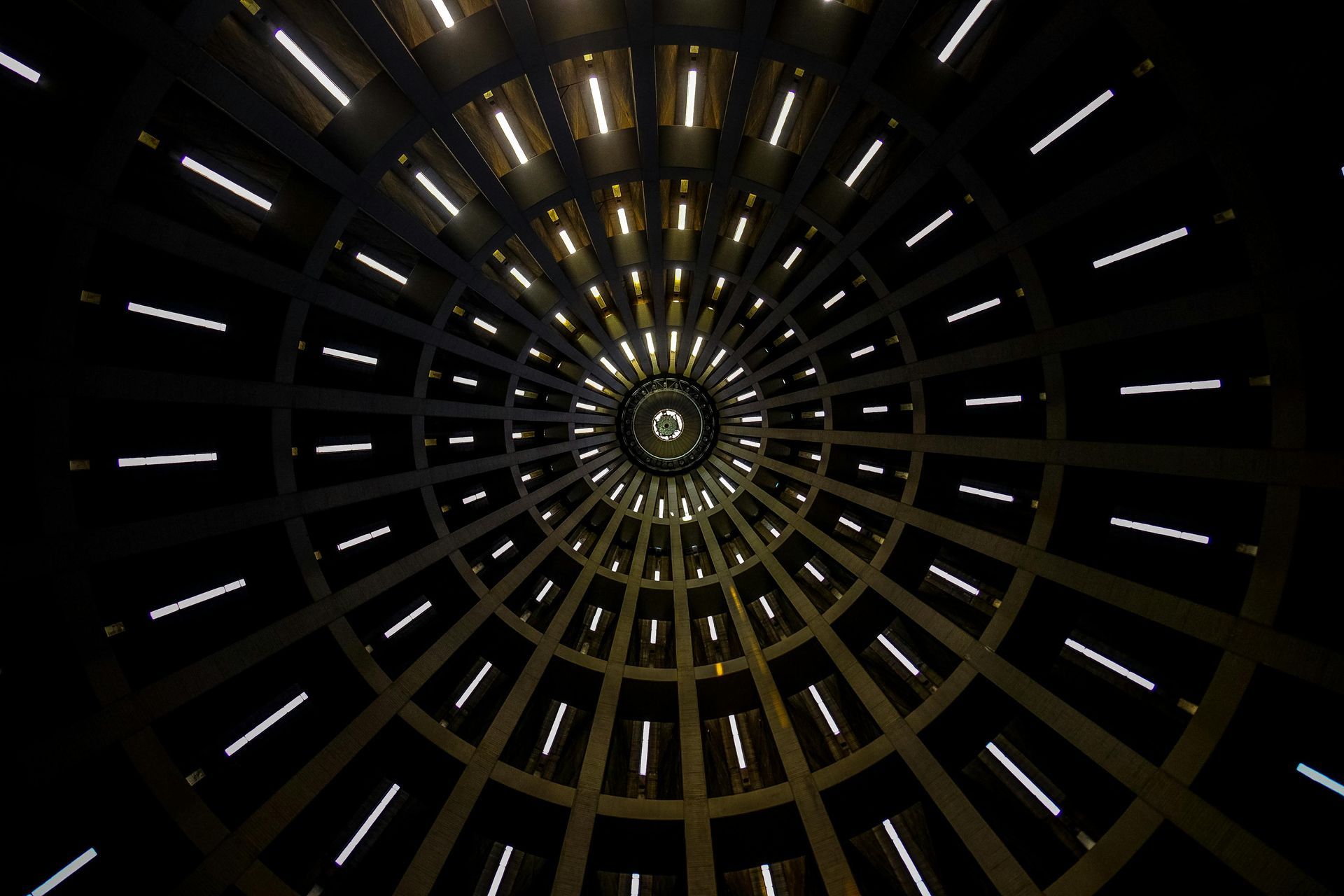 Looking up at a spiral-shaped building with lights coming out of it.