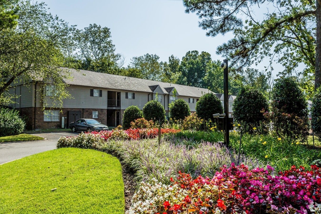 Photo of a building with a parking lot lined with flowers and plants