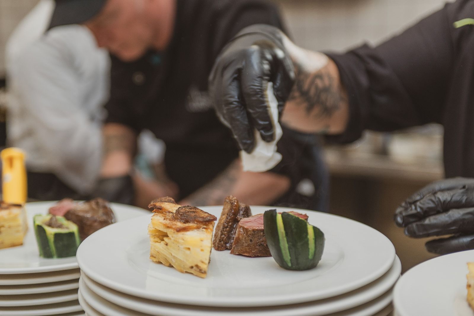 Un chef ajoute de la sauce à une assiette de nourriture.