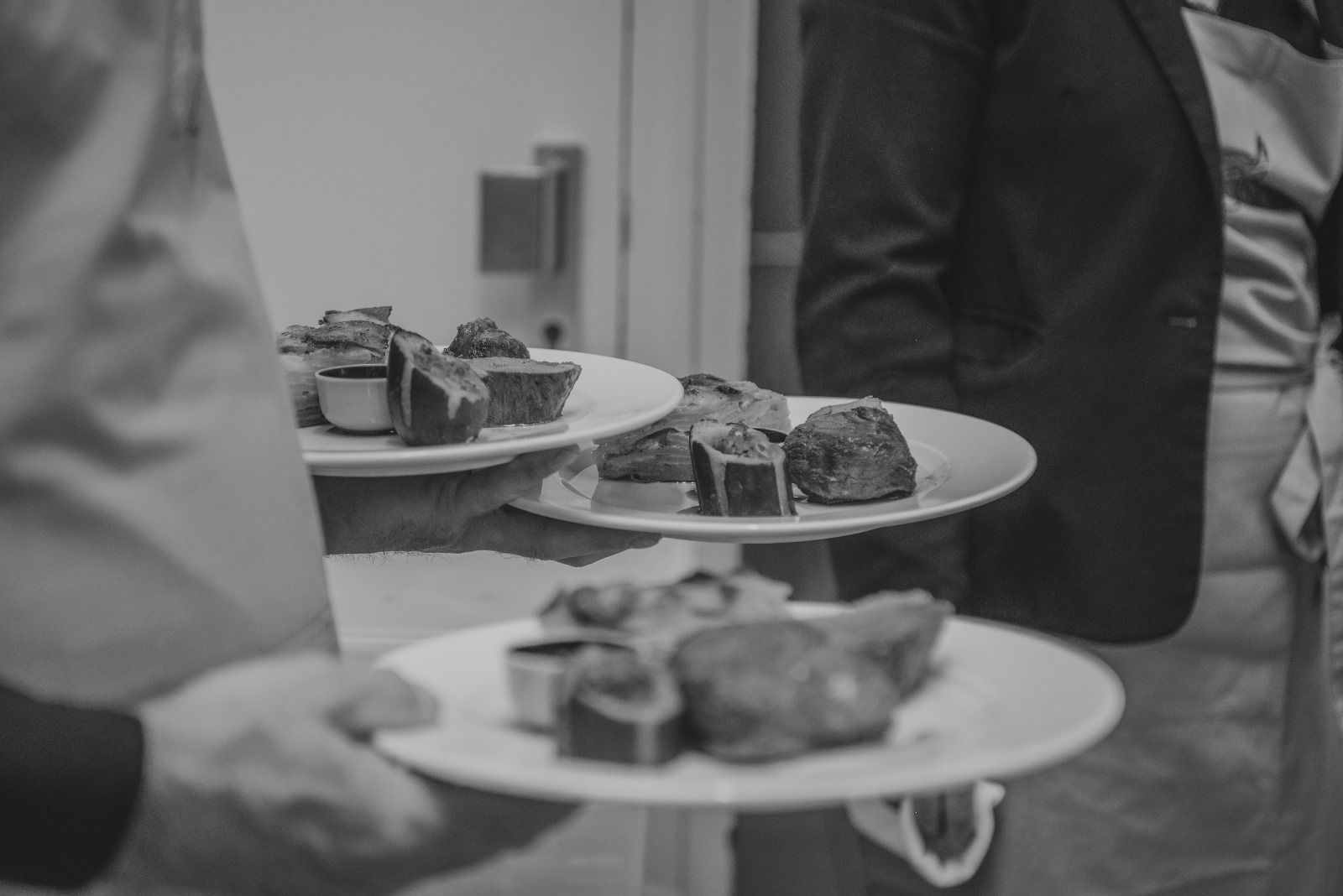 Une photo en noir et blanc d'une personne tenant des assiettes de nourriture.