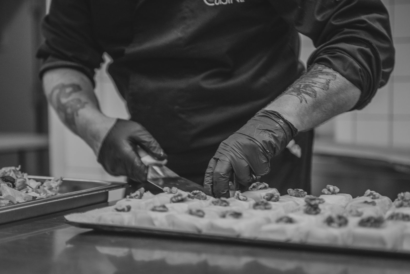 Une photo en noir et blanc d'un chef préparant de la nourriture dans une cuisine.