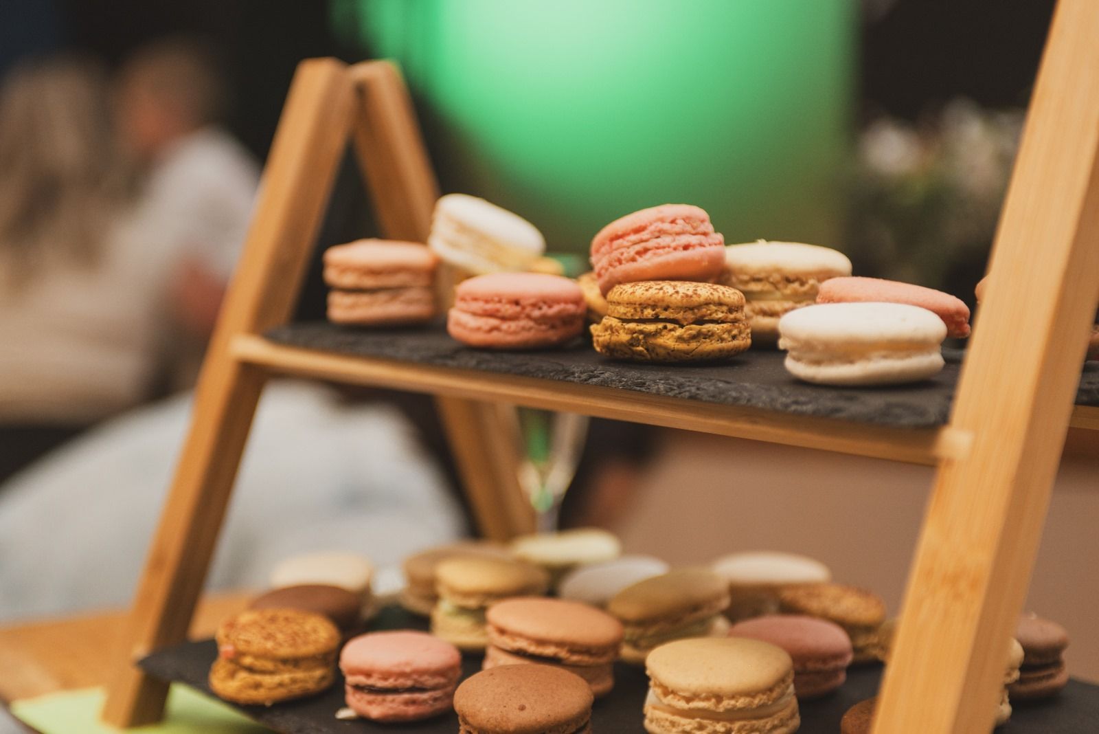 Une échelle en bois remplie de macarons sur une table.