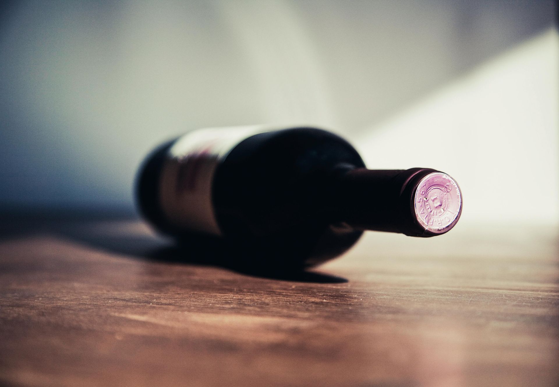 Une bouteille de vin est posée sur le côté sur une table en bois.