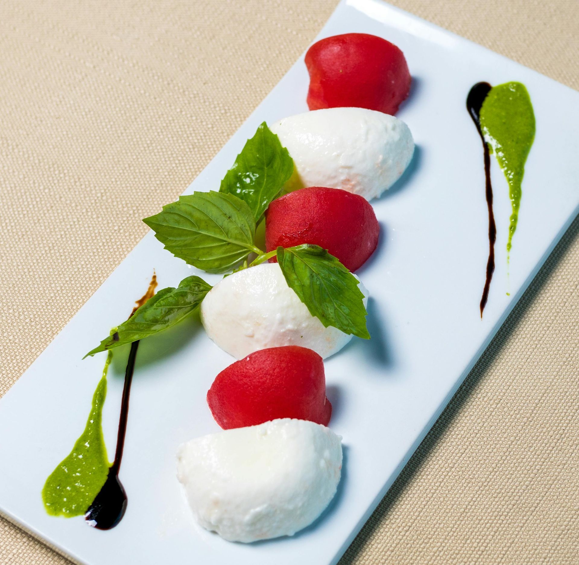 Une assiette blanche garnie de boules de mozzarella et de tomates
