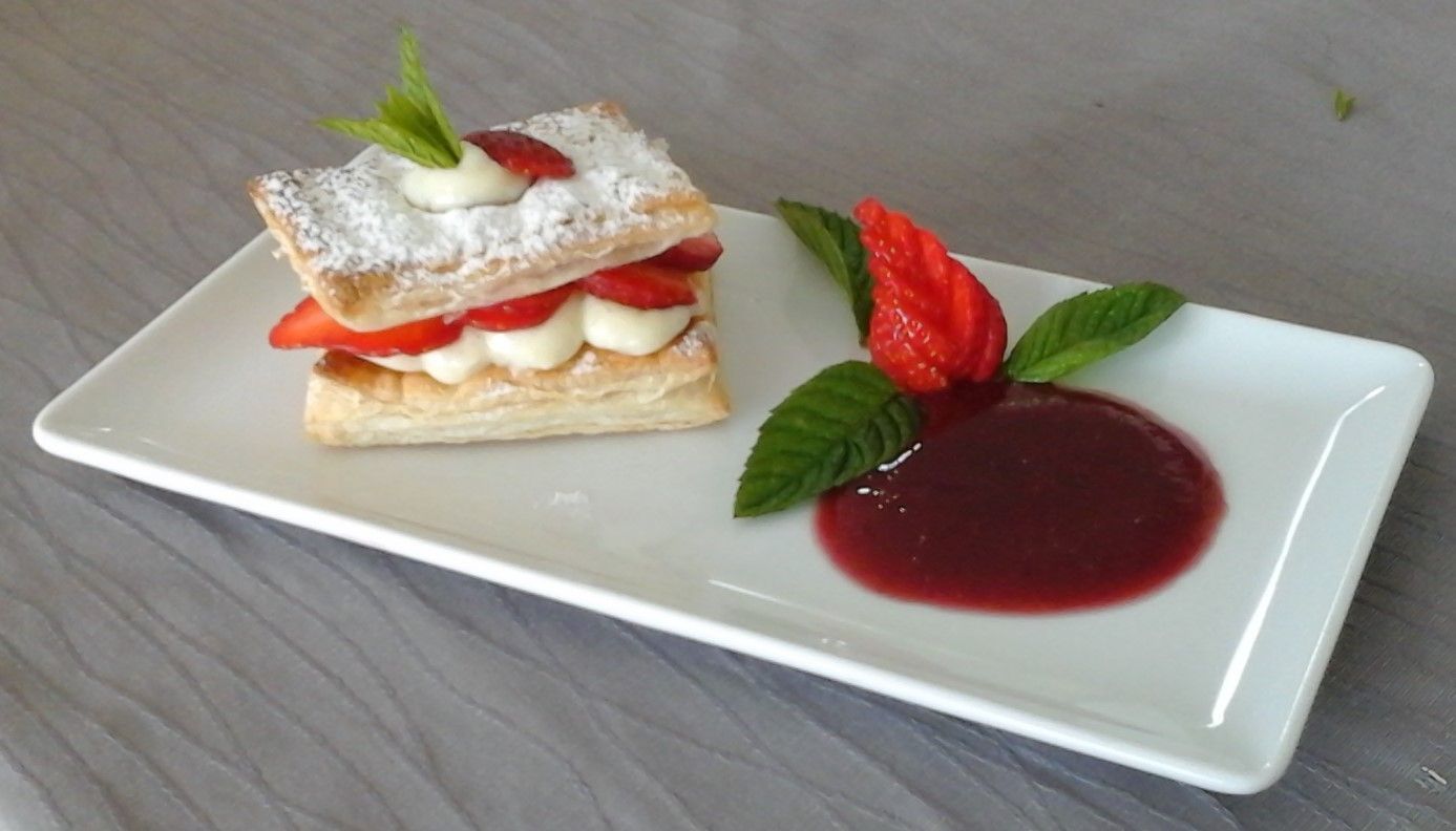 Un dessert avec des fraises et du sucre glace sur une assiette blanche