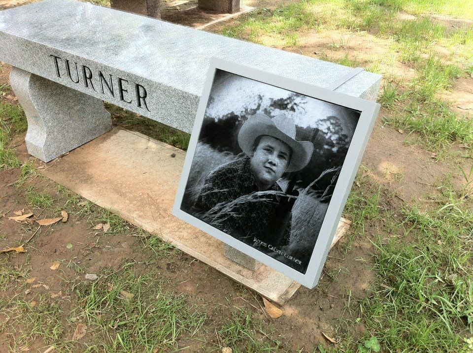 Tombe avec banc de granit portant l'inscription « TURNER » et une photo encadrée en noir et blanc d'un homme portant un chapeau de cow-boy.