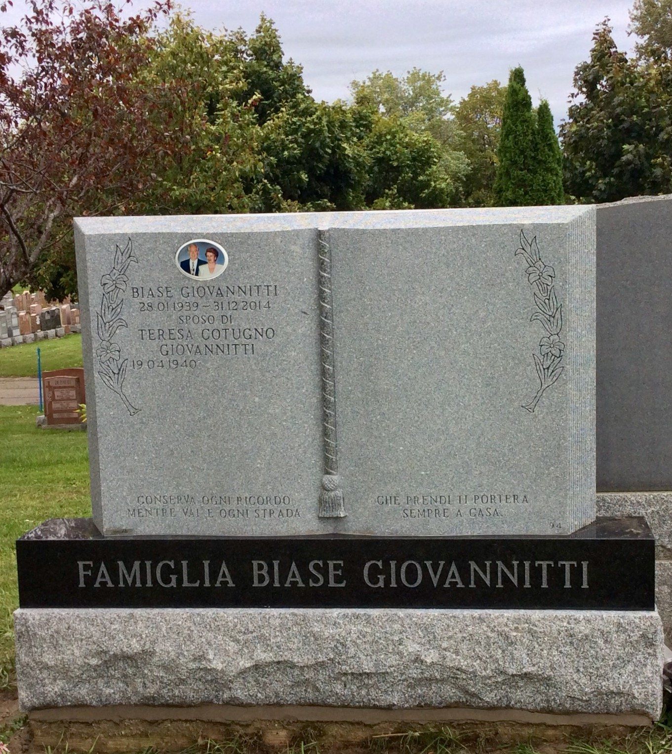 Grave marker shaped like an open book, with family names engraved. Photo of a couple is at the top.