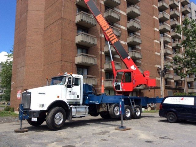 Un camion-grue est garé devant un grand bâtiment