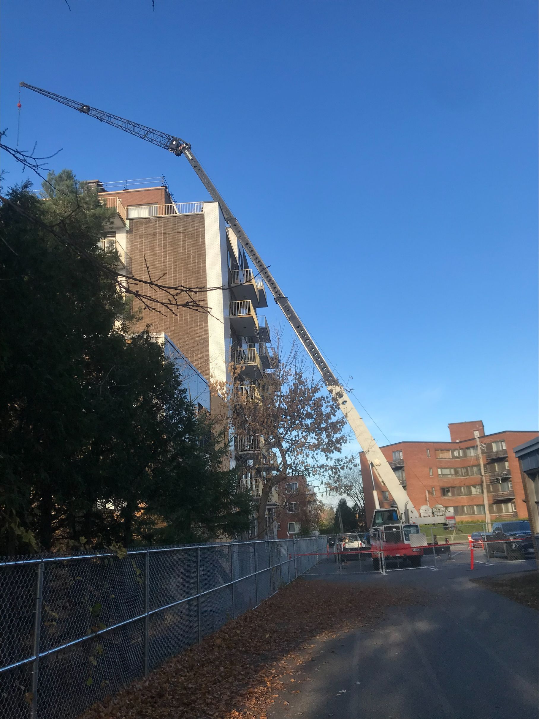 Une grue s'étend au-dessus d'un bâtiment, probablement en construction. Ciel bleu clair.