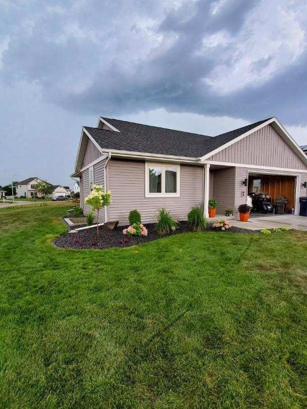 tan home with fresh landscaping and a lush green lawn