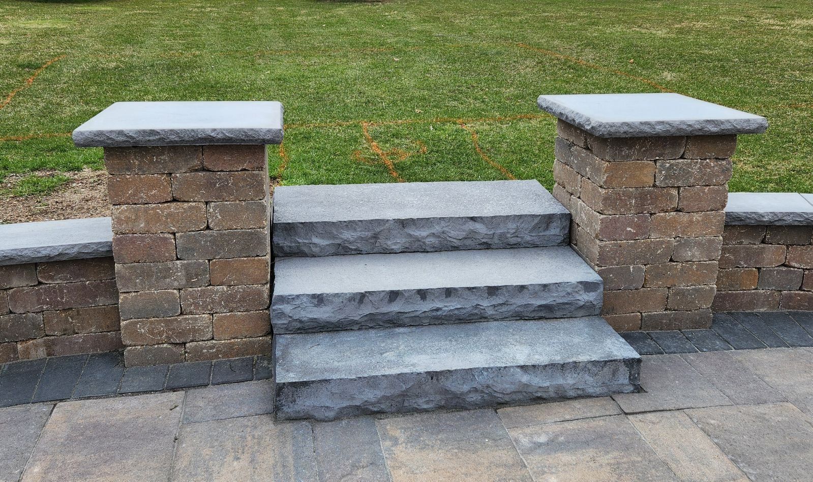 A set of stone steps leading up to a brick wall.