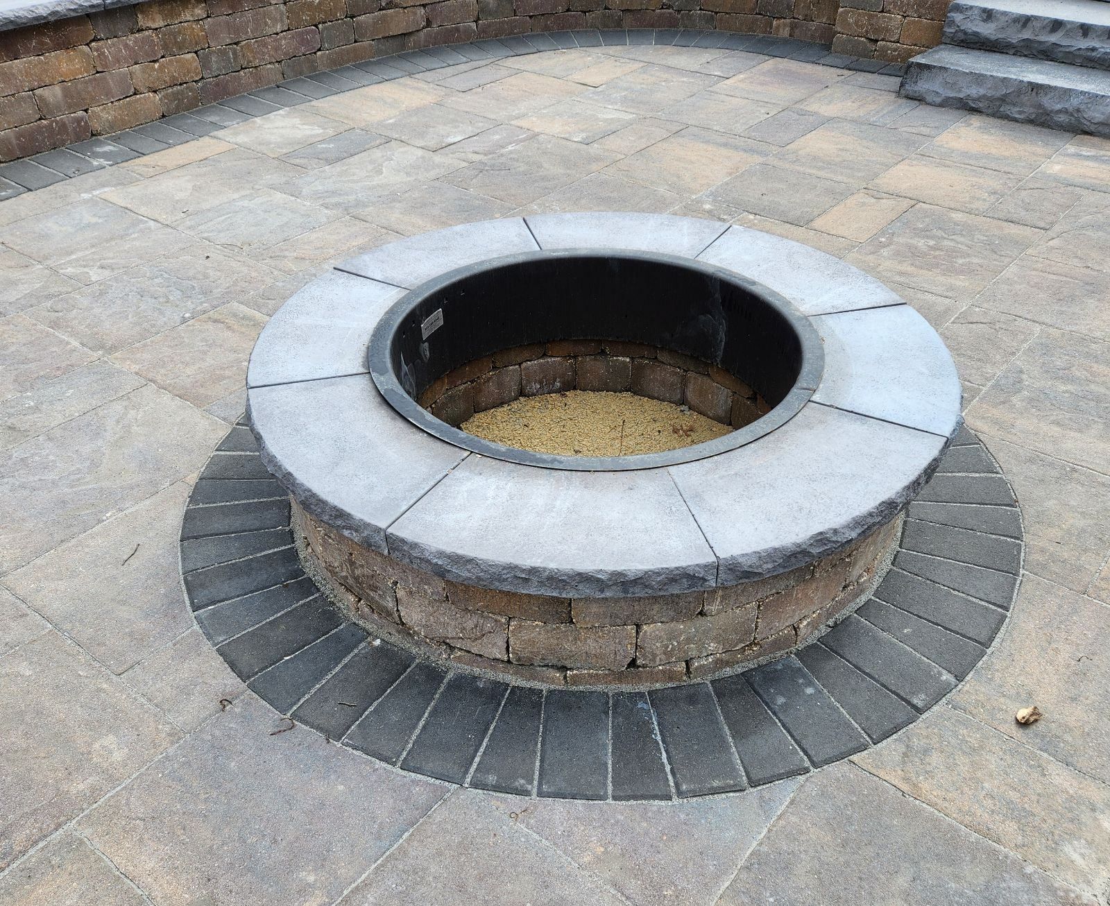 A fire pit is surrounded by bricks on a patio.