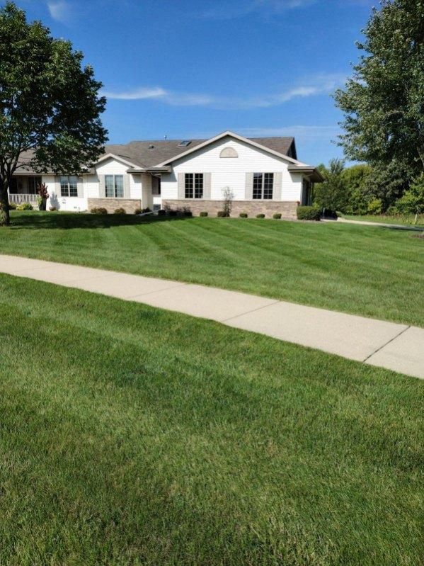 maintained lawn with sidewalk and home in background