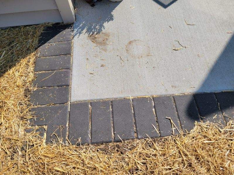 A concrete walkway with bricks and hay on the ground.