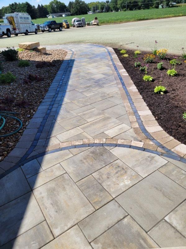 A brick walkway leading to a parking lot with a truck parked in the background.