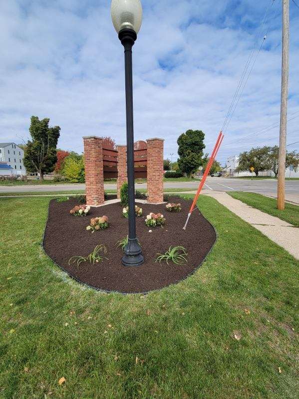 A street light is sitting in the middle of a lush green field.