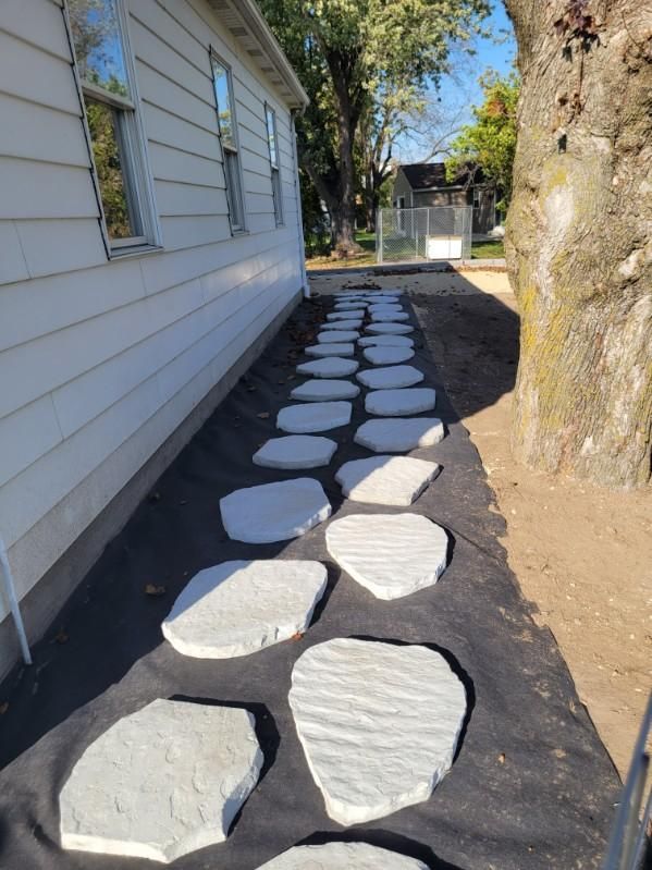 A stone walkway is being built in front of a house.