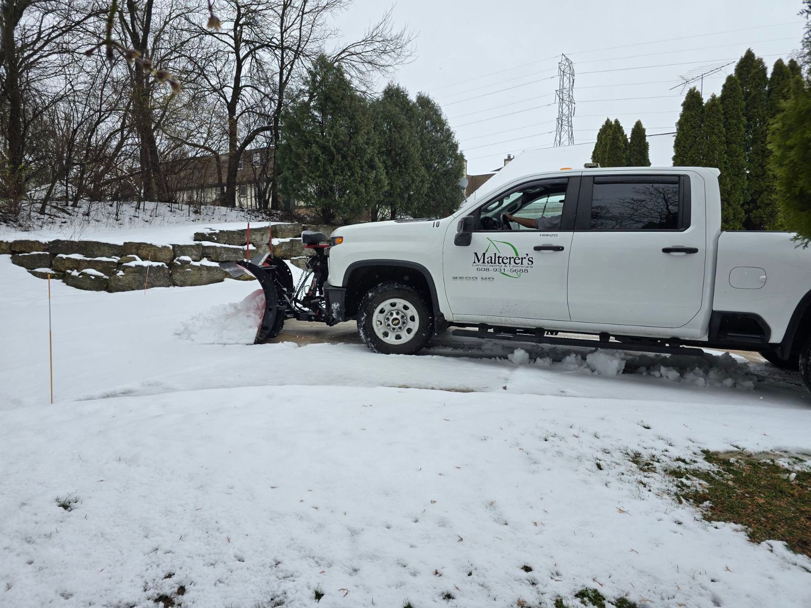 A truck with a snow plow attached to it is parked on the side of the road.