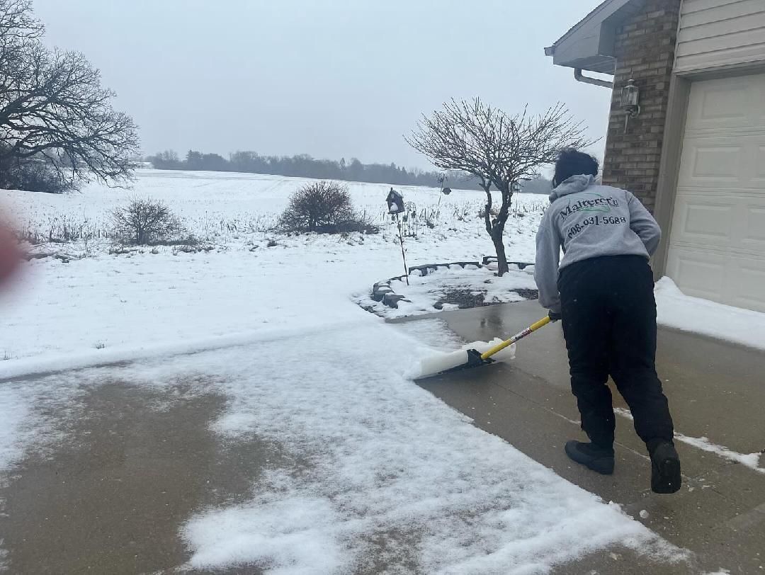 A truck with a snow plow attached to it is parked in front of a house.