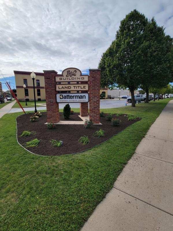 A large brick sign is in the middle of a lush green park.