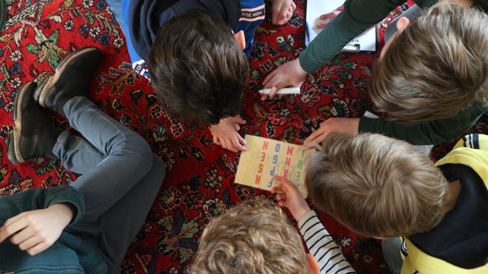 Een groepje kinderen ligt op de grond een spelletje te spelen.
