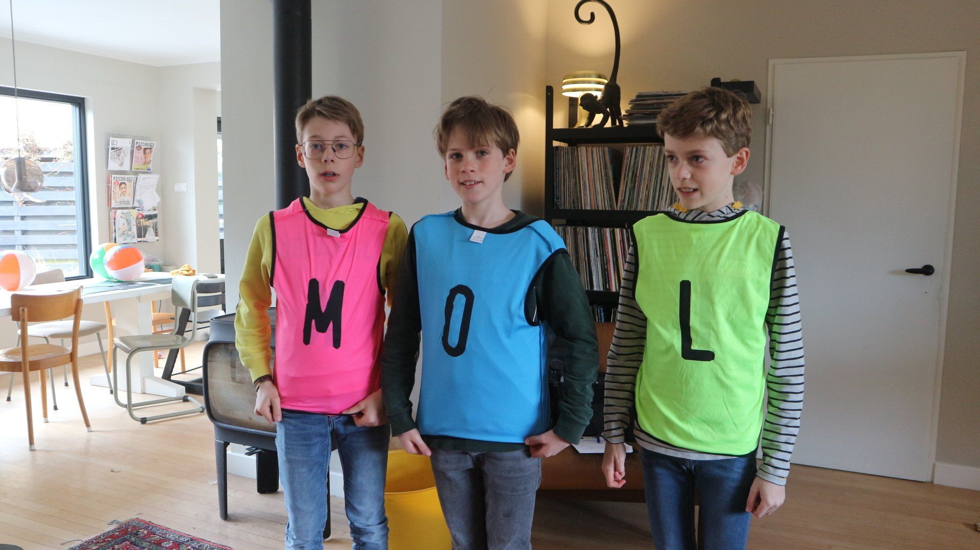 In een woonkamer staan ​​drie jongens naast elkaar.