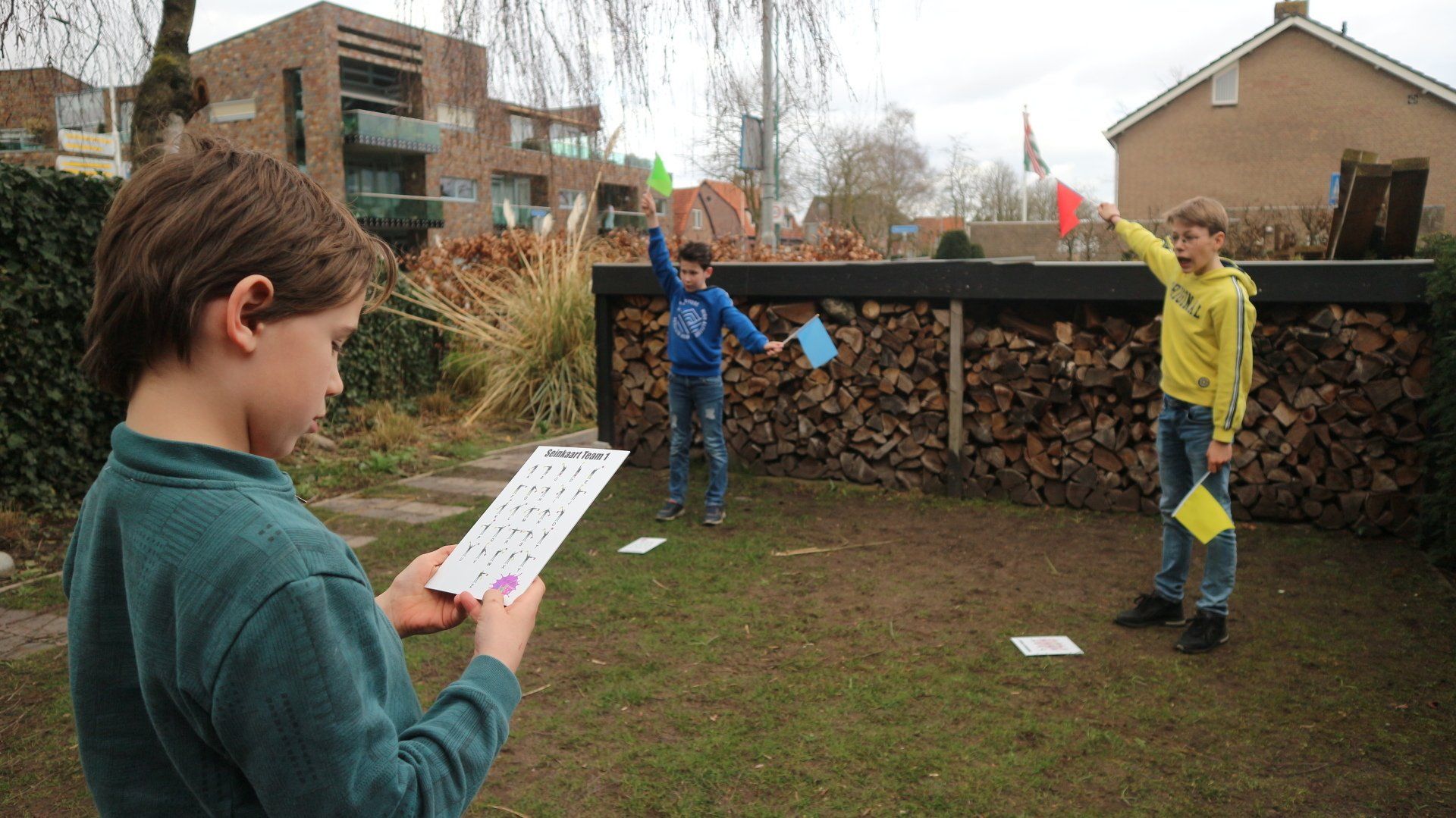 Een jongen houdt een stuk papier voor een stapel houtblokken.