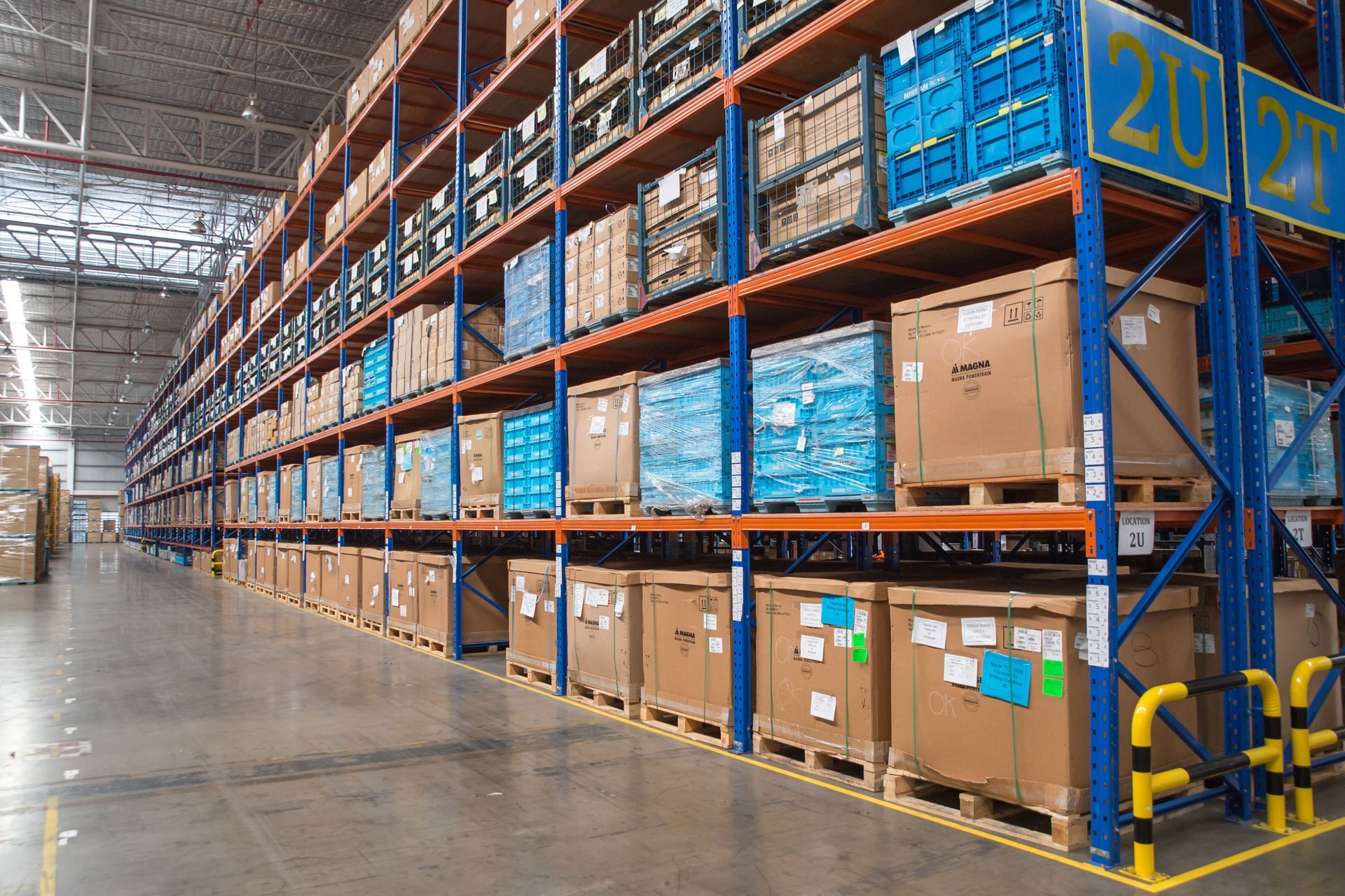 A row of red semi-trucks parked at the loading docks of a large white warehouse facility.