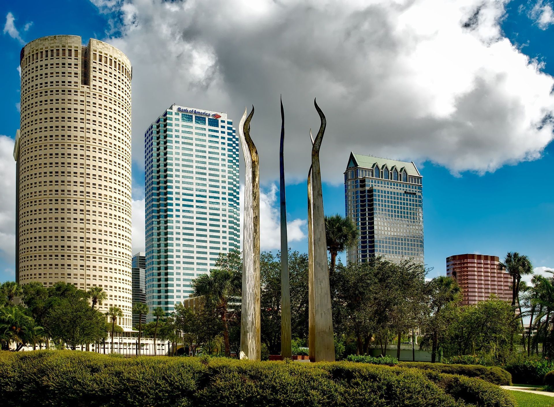 Modern skyscraper with angular, mirrored windows and light blue/gray metal framework.