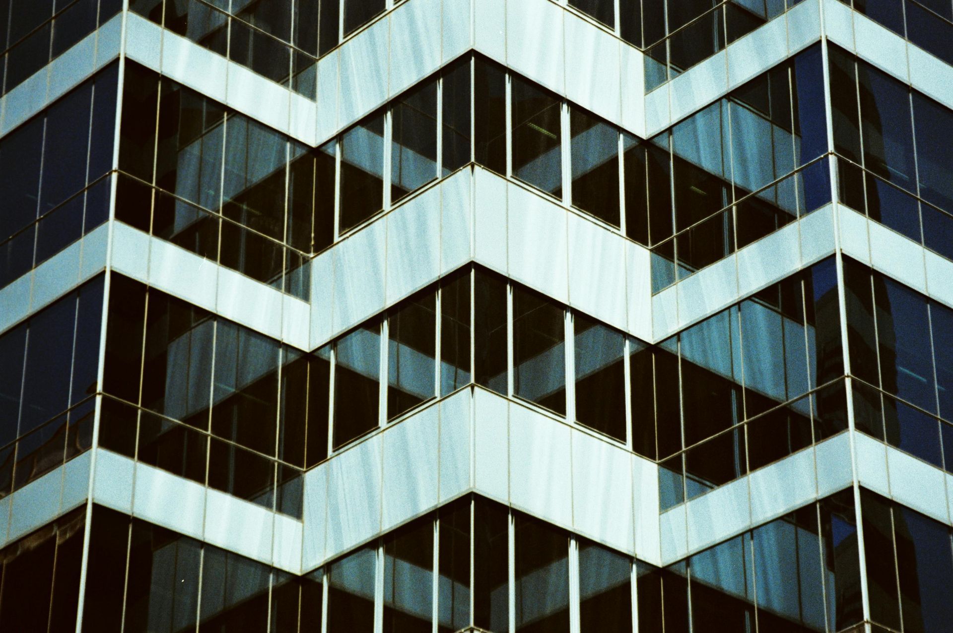 Angular, glass-walled office building with a zigzag design; blues, whites, and reflections.