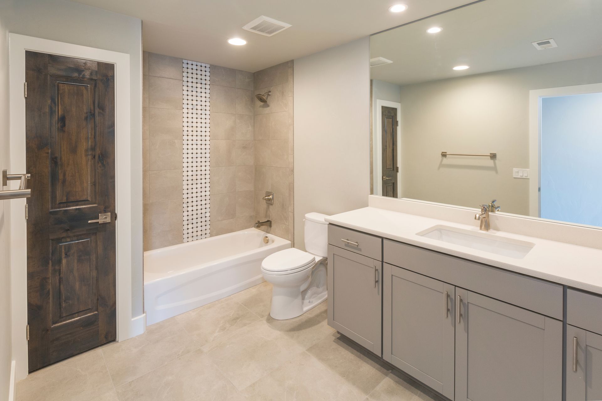 Bathroom with gray cabinets, white countertop, and a wooden door.