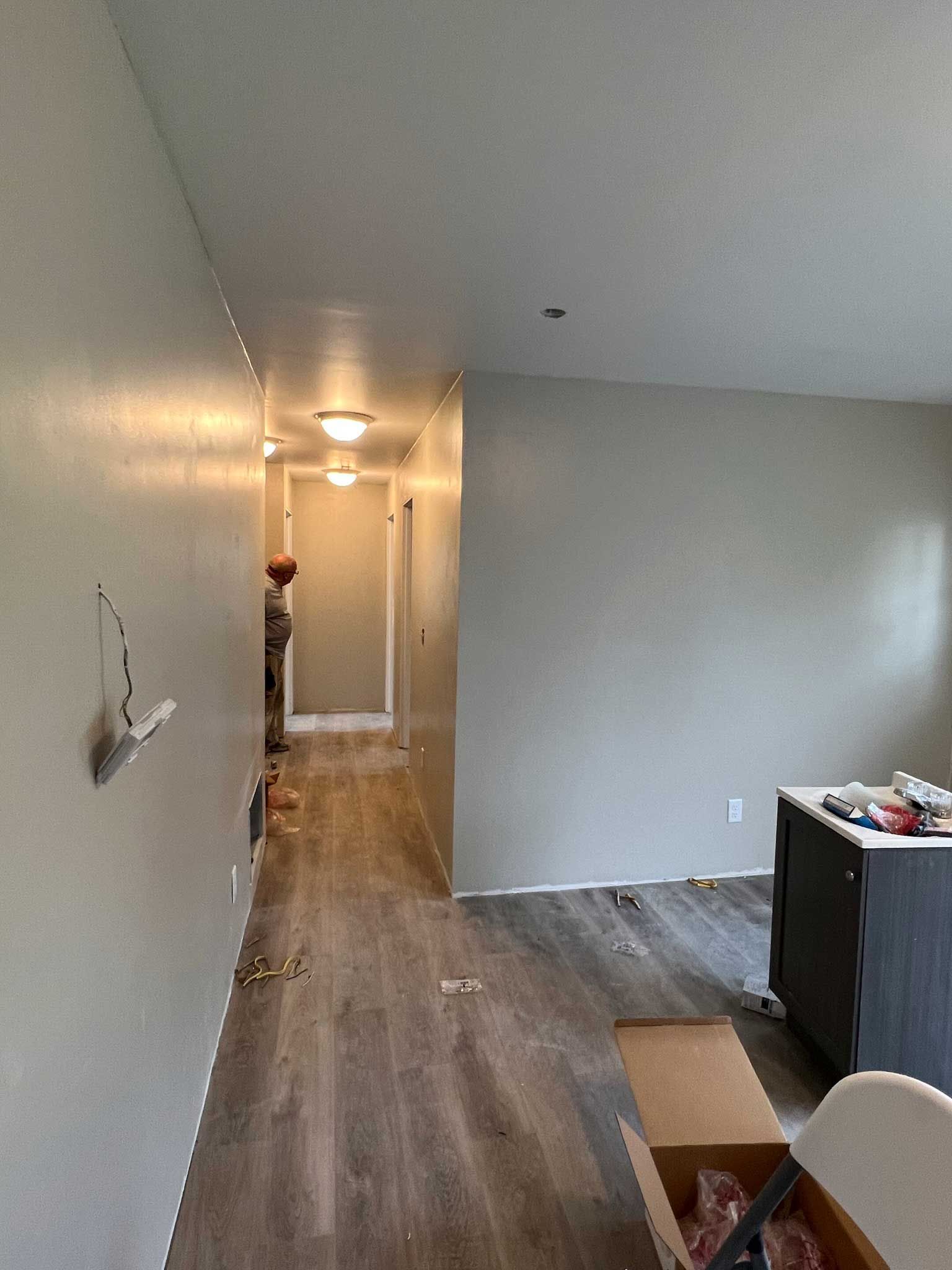 Hallway with gray walls and wood-look flooring, leading to a doorway with a fireplace.